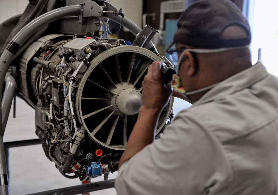 Willy Latham, M1 Support Services propulsion mechanic, inspects a General Electric J85-GE-5 turbojet engine
